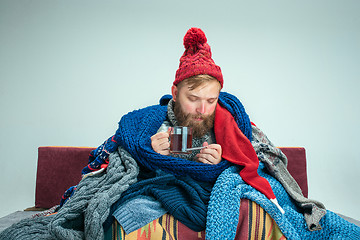 Image showing Bearded Man with Flue Sitting on Sofa at Home. Healthcare Concepts.