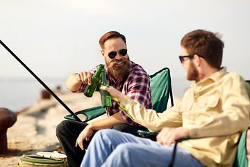 Image showing happy friends fishing and drinking beer on pier