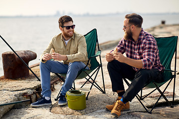 Image showing happy friends fishing and eating sandwiches