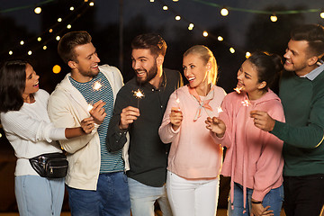 Image showing happy friends with sparklers at rooftop party