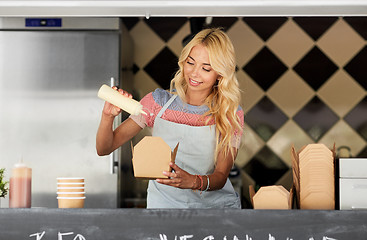 Image showing happy saleswoman making wok at food truck