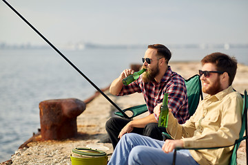 Image showing happy friends fishing and drinking beer on pier