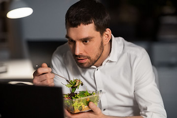 Image showing businessman with computer eating at night office