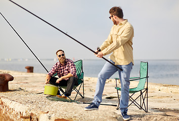 Image showing happy friends with fishing rods on pier