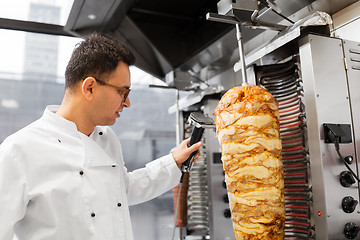 Image showing chef slicing doner meat from spit at kebab shop