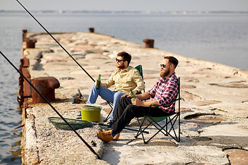 Image showing happy friends fishing and drinking beer on pier