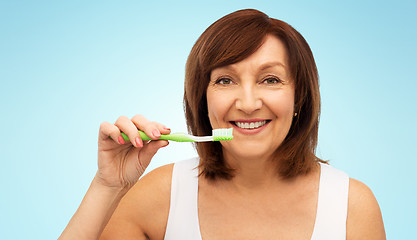 Image showing senior woman with toothbrush brushing her teeth