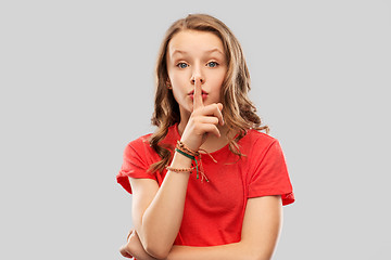 Image showing teenage girl in red t-shirt with finger on lips