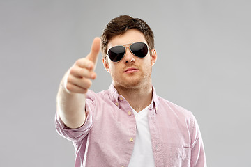 Image showing young man in sunglasses making hand gun gesture