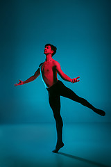 Image showing The male athletic ballet dancer performing dance on blue background. Studio shot. Ballet concept. Fit young man. Caucasian model