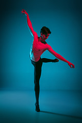 Image showing The male athletic ballet dancer performing dance on blue background. Studio shot. Ballet concept. Fit young man. Caucasian model