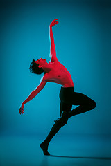 Image showing The male athletic ballet dancer performing dance on blue background. Studio shot. Ballet concept. Fit young man. Caucasian model