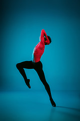 Image showing The male athletic ballet dancer performing dance on blue background. Studio shot. Ballet concept. Fit young man. Caucasian model