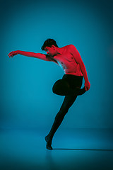 Image showing The male athletic ballet dancer performing dance on blue background. Studio shot. Ballet concept. Fit young man. Caucasian model