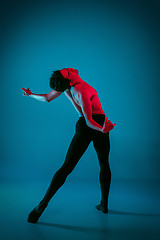 Image showing The male athletic ballet dancer performing dance on blue background. Studio shot. Ballet concept. Fit young man. Caucasian model