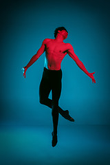 Image showing The male athletic ballet dancer performing dance on blue background. Studio shot. Ballet concept. Fit young man. Caucasian model