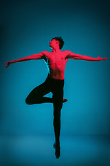 Image showing The male athletic ballet dancer performing dance on blue background. Studio shot. Ballet concept. Fit young man. Caucasian model