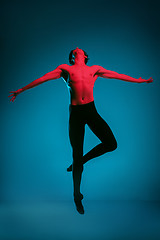 Image showing The male athletic ballet dancer performing dance on blue background. Studio shot. Ballet concept. Fit young man. Caucasian model