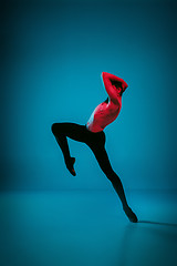 Image showing The male athletic ballet dancer performing dance on blue background. Studio shot. Ballet concept. Fit young man. Caucasian model