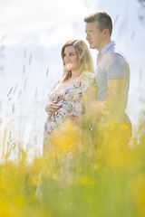 Image showing Young happy pregnant couple hugging in nature.