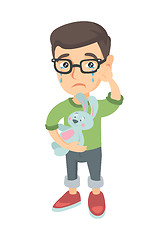 Image showing Caucasian boy in glasses crying and holding toy.