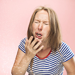 Image showing Young woman sneezing, studio portrait