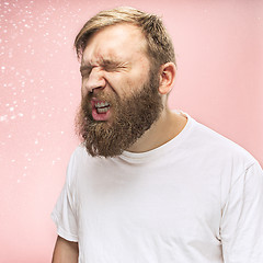 Image showing Young handsome man with beard sneezing, studio portrait