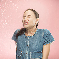 Image showing Young woman sneezing, studio portrait