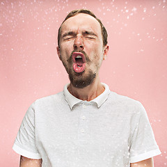 Image showing Young handsome man with beard sneezing, studio portrait