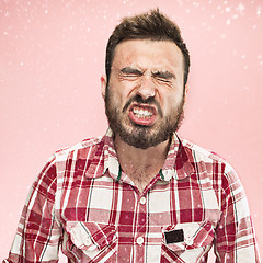 Image showing Young handsome man with beard sneezing, studio portrait