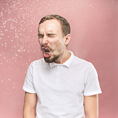 Image showing Young handsome man with beard sneezing, studio portrait