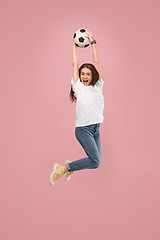 Image showing Forward to the victory.The young woman as soccer football player jumping and kicking the ball at studio on pink