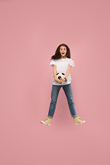 Image showing Forward to the victory.The young woman as soccer football player jumping and kicking the ball at studio on pink