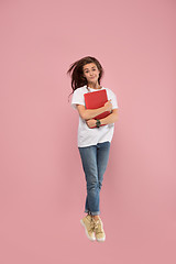 Image showing Image of young woman over pink background using laptop computer or tablet gadget while jumping.