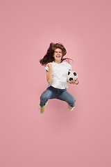 Image showing Forward to the victory.The young woman as soccer football player jumping and kicking the ball at studio on pink