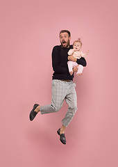 Image showing The studio shot of little girl sitting on his father. isolated on pink