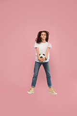 Image showing Forward to the victory.The young woman as soccer football player jumping and kicking the ball at studio on pink