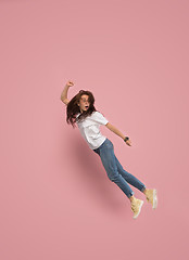 Image showing Freedom in moving. Pretty young woman jumping against pink background