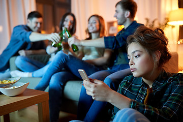 Image showing sad young woman with smartphone at home party