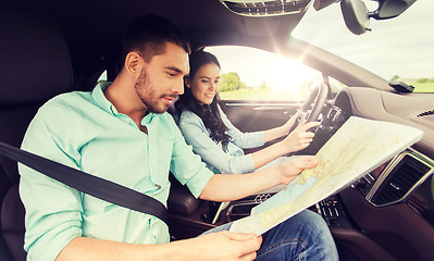 Image showing happy man and woman with road map driving in car