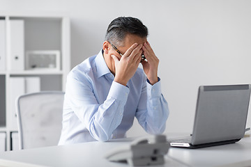 Image showing stressed businessman with laptop working at office