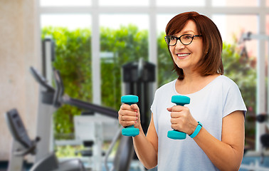 Image showing happy old woman with dumbbells exercising in gym