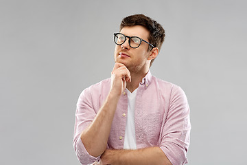 Image showing thinking young man in glasses over grey background