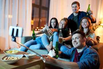 Image showing friends taking picture by selfie stick at home