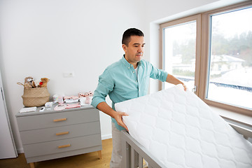 Image showing father arranging baby bed with mattress at home