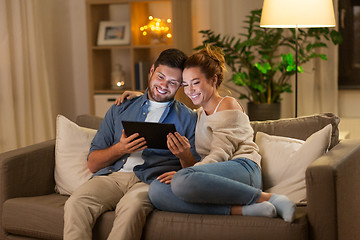 Image showing happy couple using tablet pc at home in evening