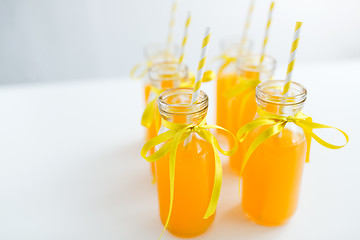 Image showing orange juice in glass bottles with paper straws