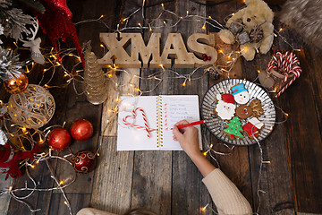 Image showing Writing a Christmas list among Christmas decorations and gingerb