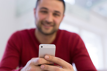 Image showing young man using a mobile phone  at home