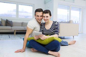 Image showing Young Couple using digital tablet on the floor